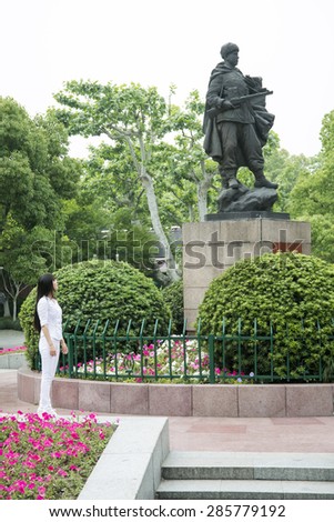 HANGZHOU, CHINA - MAY 3, 2015: Chinese woman admiring a statue of a soldier in honor of the Chinese army men who participated in the Korean War, defending North Korea.
