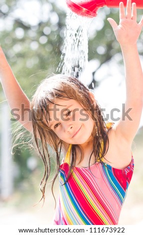 Happy little  girl enjoying in summer day and playing with water