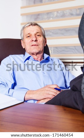 Senior businessman lying on his office chair with his feet on the desk