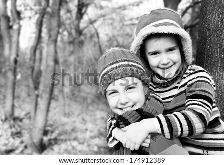 Two little sister girls hug playing in the forest