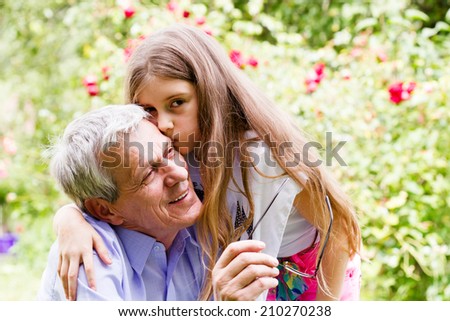 Little girl whispering her grandfather a secret to ear