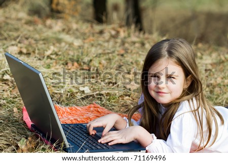 Little girl with laptop in forest