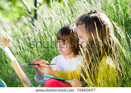 Two little girls painting in nature