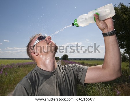 Male athlete splashing water on his face to refresh on a hot summer day.