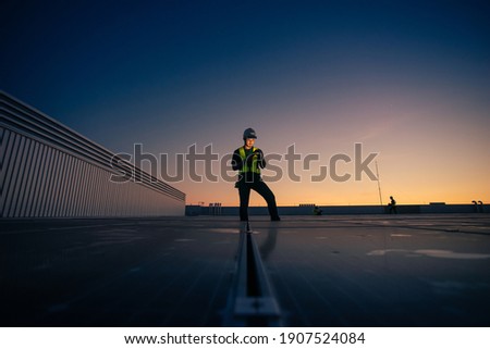 Asian man engineer service check installation solar cell on the roof of factory on the morning. Silhouette technician with solar cell on the roof of factory under morning sky. Technology solar cell.