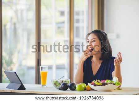 Happy Asian woman vegetarian healthy eating salad food and use tablet on the table. Young woman vegetarian. Vegetables and fruits. Vegan food.