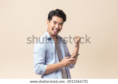 Photo of Portrait young Asian man handsome happy smile in formal shirt using smartphone trading or chatting on brown isolated studio background.