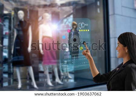 smart retail, shopping online technology concept, woman try to use smart display with virtual or augmented reality in the shop or retail to choose select ,buy cloths and give a rating of products 
