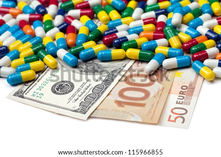 American, Canadian and European currency covered by pills isolated on a white background.