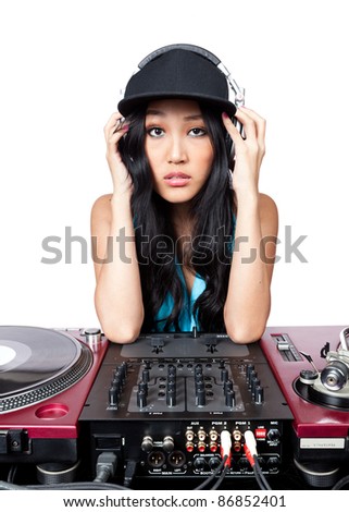 A young female Asian DJ posing in for a photo in front of a mixer and turntables