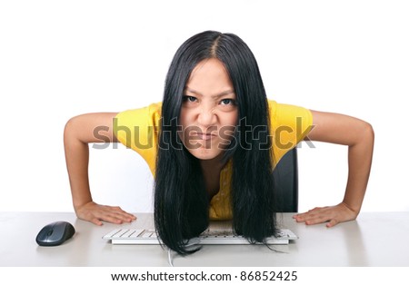 A young girl making a mean face while at desk with computer and keyboard