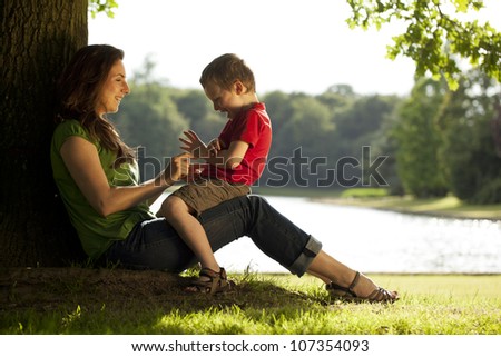 Mum and son playing by tree on a sunny day in the park