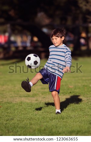 Young boy kicking a soccer ball in the park - with copy space
