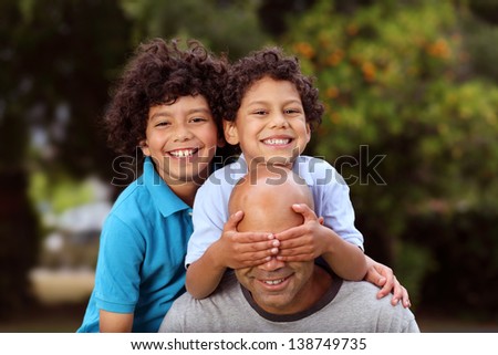 A father plays with his two sons in the back yard or garden