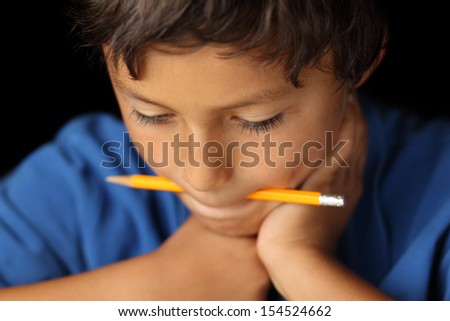 Portrait of young school boy with a pencil in his mouth with chiaroscuro lighting - shallow depth of field