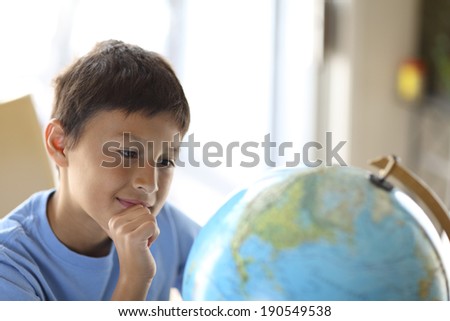 Young boy looking at a globe dreams of traveling the world - very shallow depth of field