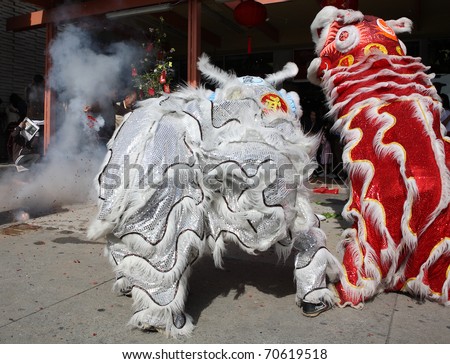 ROSEMEAD, CA - FEBRUARY 5, 2011:  A man sets off fire crackers to scare away evil spirits near two lion dancers for Chinese New Year outside a shopping centeron January 24, 2011 in Rosemead, CA.