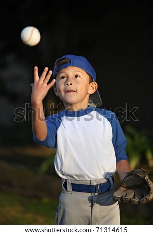 Happy smiling young Latino boy dressed in blue baseball sleeves with cap, glove and ball