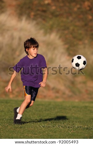 Boy playing with soccer ball in early evening sunlight