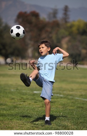 A young boy kicks a soccer ball in a park setting