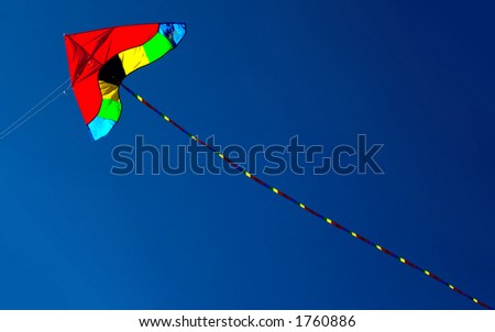 kite in red yellow and green against intense blue sky. With space for text