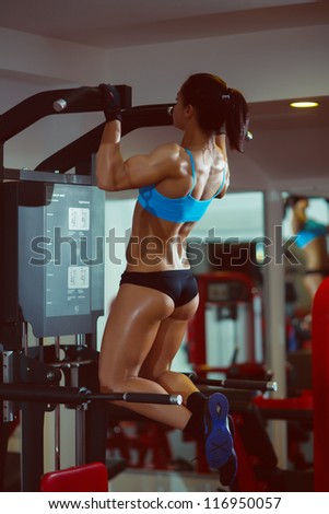 Muscle sport girl pull up on bars