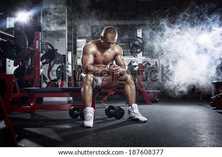 very power athletic guy, relaxing after workout in the gym