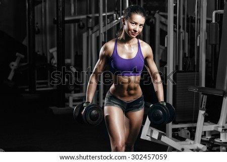 sexy young girl resting doing sport workout exercises with dumbbells. Fitness woman in sport wear with perfect fitness body in gym