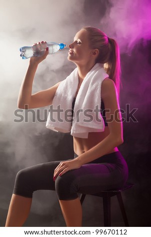 Fitness girl rest and drink water on smoke background