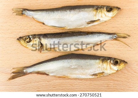 Three smoked fish on board made of beech