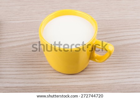 Yellow cup of milk on wooden table