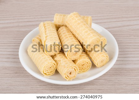Heap of wafer rolls in glass saucer on table