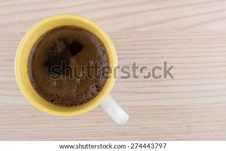 Hot cup of organic coffee with foam on wooden table, top view