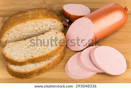Pieces of bread and cooked sausages on wooden bamboo board