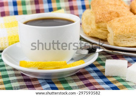 Black coffee, lemon and sugar, flaky biscuits close up on tablecloth