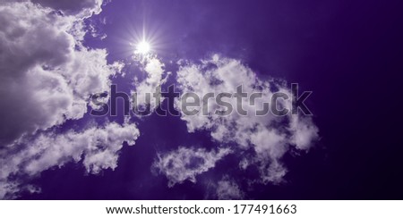 Whit puffy clouds on sunny purple sky