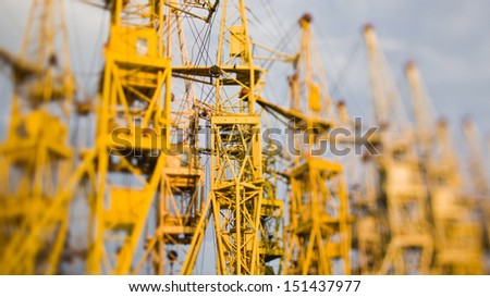 Tilt-shift photo of yellow building cranes and sky
