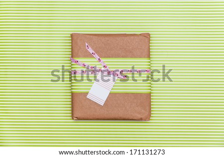 A green box tied with a pink satin ribbon bow with ladybirds and visit card on it