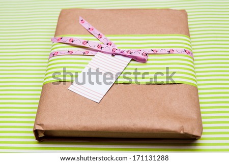 A green box tied with a pink satin ribbon bow with ladybirds and visit card on it