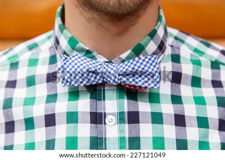 Vintage bowtie on a young fashion male in shirt in front of wooden background