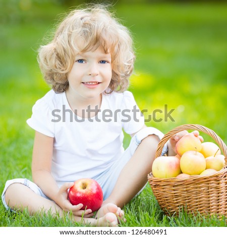Happy child eating apple outdoors in spring park