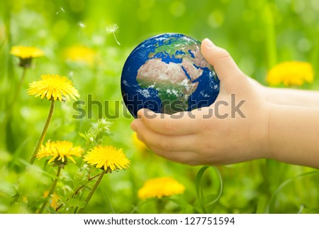 Planet Earth in children`s hands against spring flowers. Elements of this image furnished by NASA