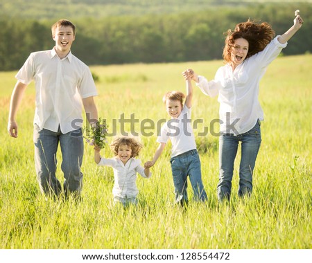 Active happy family jumping outdoors in spring green field
