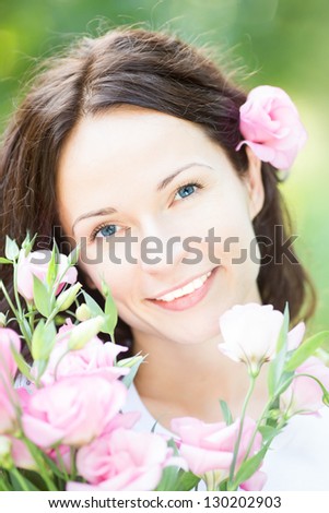 Young beautiful woman with bouquet of spring flowers against green background. Mothers day concept. Family holiday