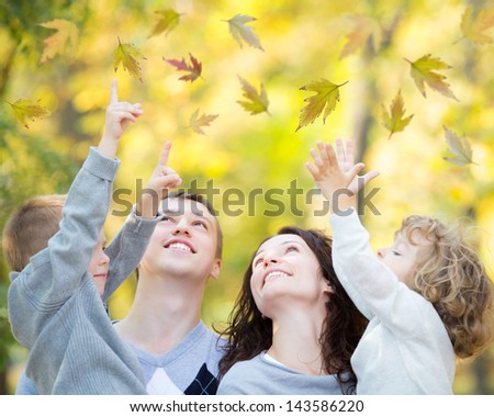 Happy family having fun outdoors in autumn park against blurred leaves background