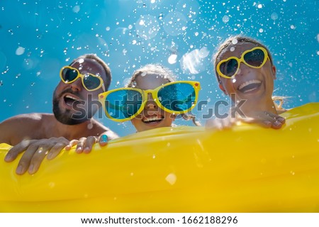 Family having fun on summer vacation. People jumping in swimming pool. Active lifestyle concept. Spring break!