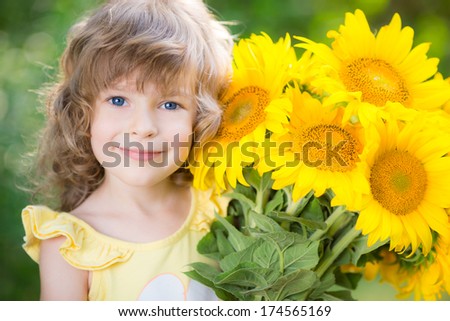 Happy child with bouquet of beautiful sunflowers against green background. Spring family holiday concept. Mother`s day