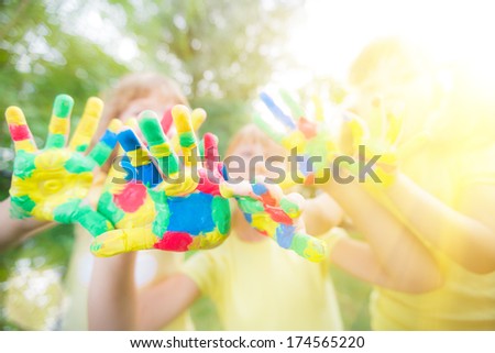 Group of friends with painted hands against green spring background