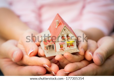 Family holding house in hands. Real estate concept