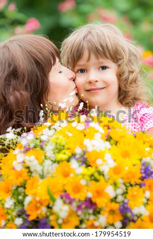 Woman and child with bouquet of flowers against green background. Spring family holiday concept. Mother\'s day